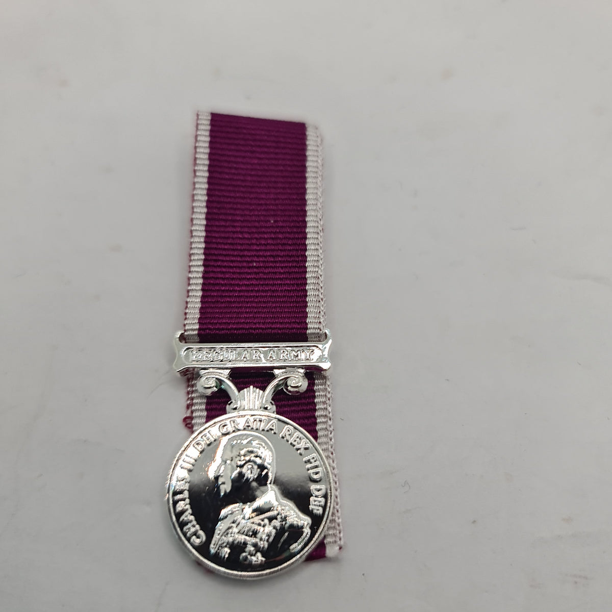 Army miniature medal with a King's Head design, attached to a purple ribbon with a silver-colored border on the top.